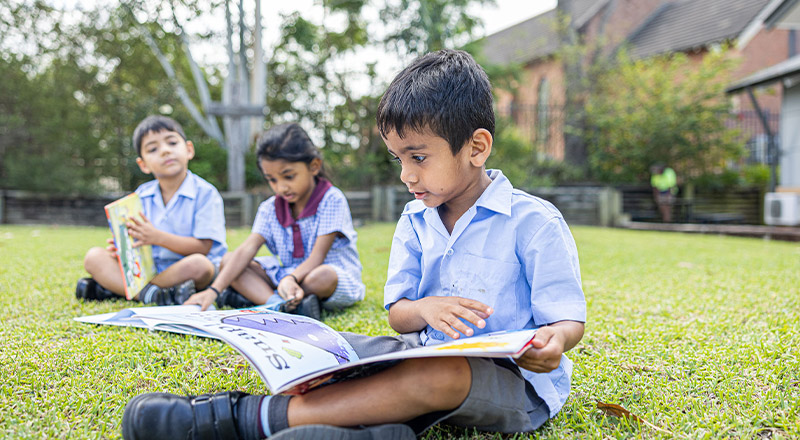 Students reading reading outside together at St John's Primary School Riverstone