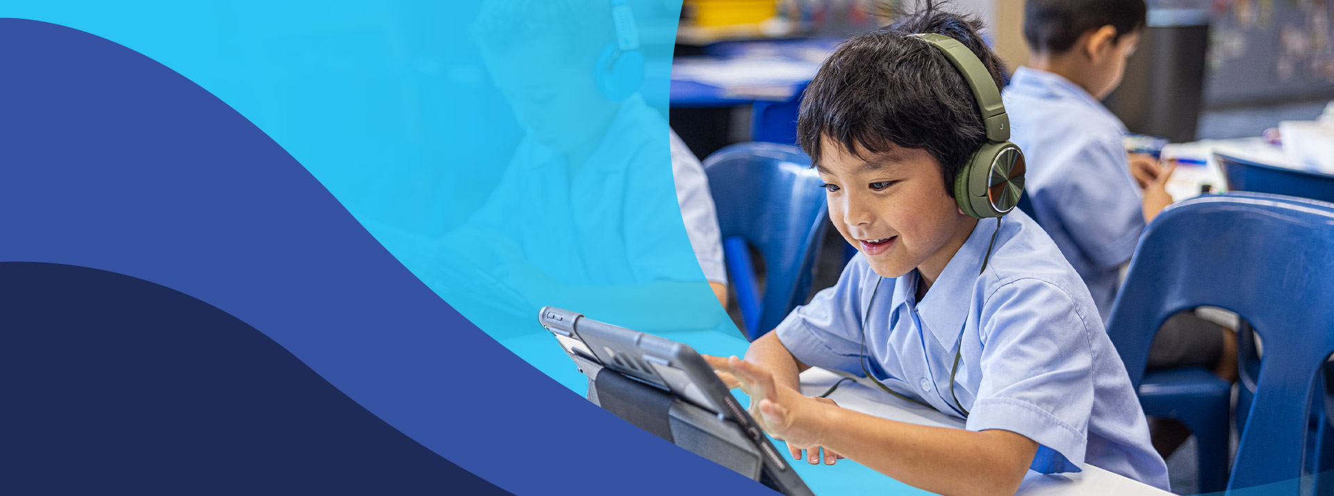 Student wearing headphones using his tablet in the classroom at St John's Primary School Riverstone