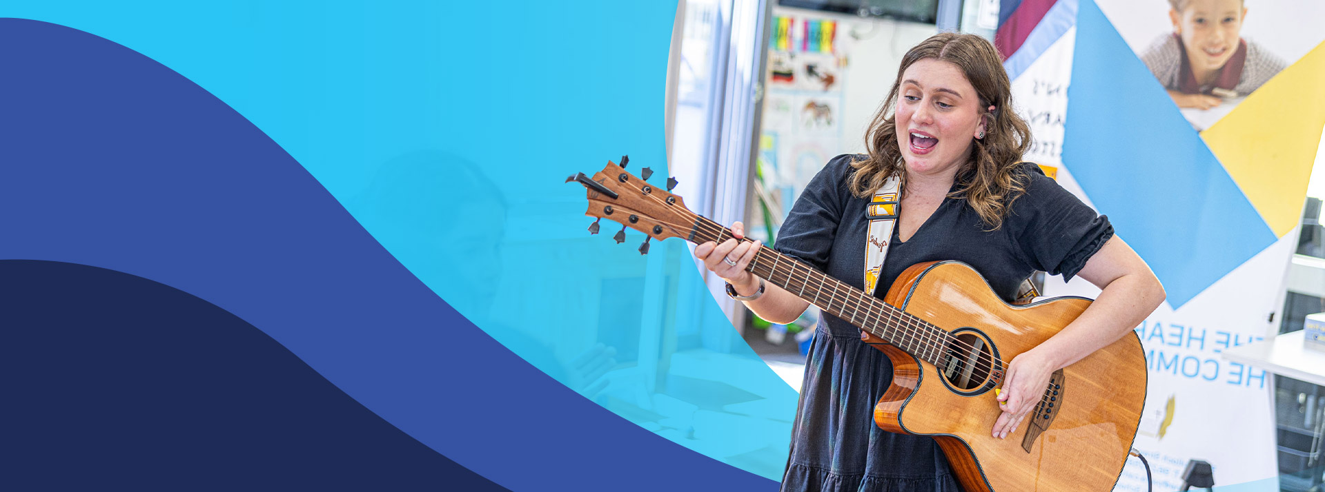 Teacher playing the guitar in the classroom at St John's Primary School Riverstone