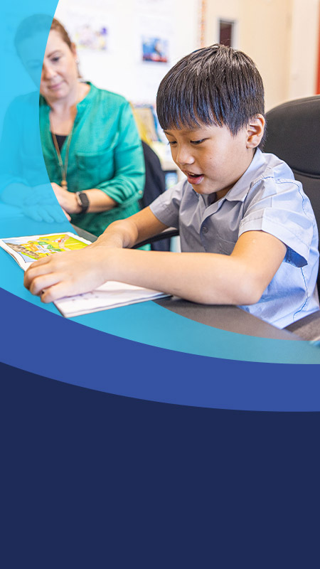 Teacher reading with her student in the classroom at St John's Primary School Riverstone