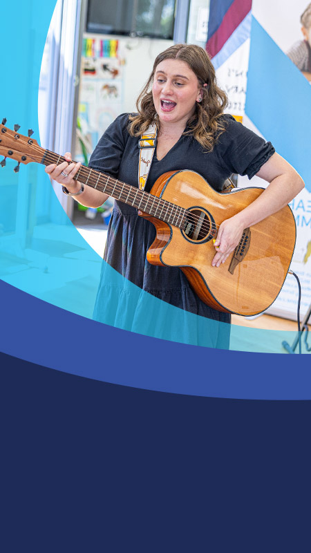 Teacher playing the guitar in the classroom at St John's Primary School Riverstone