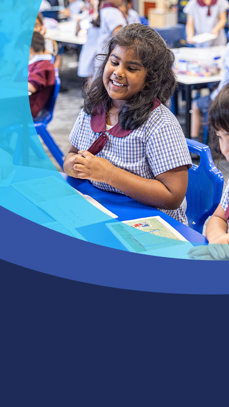 Student smiling with her classmates in the classroom at St John's Primary School Riverstone