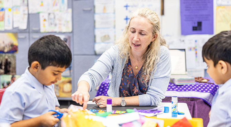 Teacher assisting her students in the classroom at St John's Primary School Riverstone