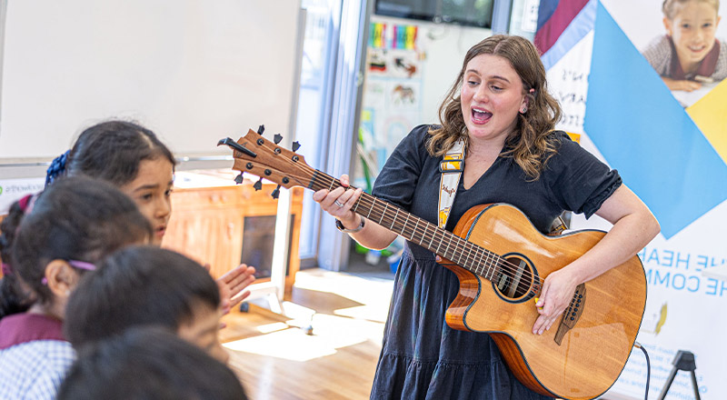 Teacher playing the guitar in the classroom at St John's Primary School Riverstone
