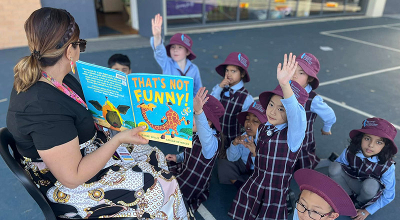 Teacher reading to her students on the playground at St John's Primary School Riverstone