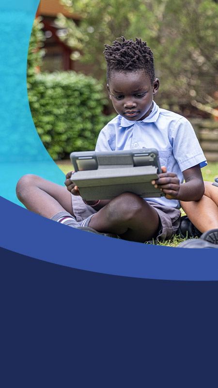 Students working together on their tablets on the grass at St John's Primary School Riverstone