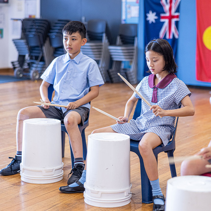 Students playing drums on buckets together at St John's Primary School Riverstone