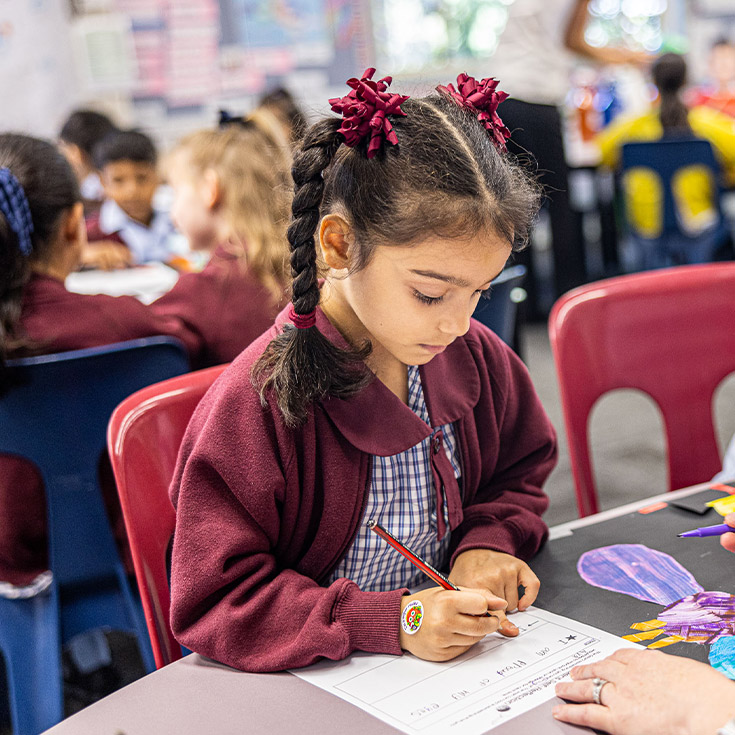 Student practising her handwriting in the classroom at St John's Primary School Riverstone