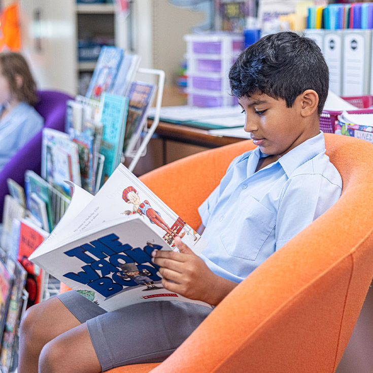 Student reading a book in the library at St John's Primary School Riverstone